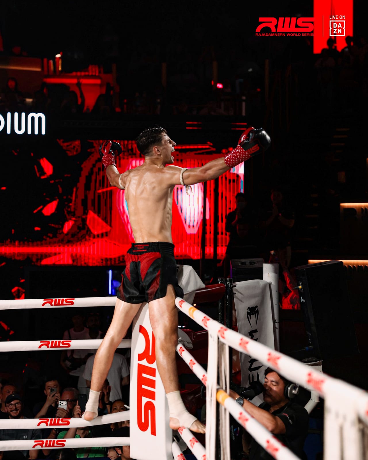 Louie Doherty climbs the ropes with both arms raised to celebrate a win